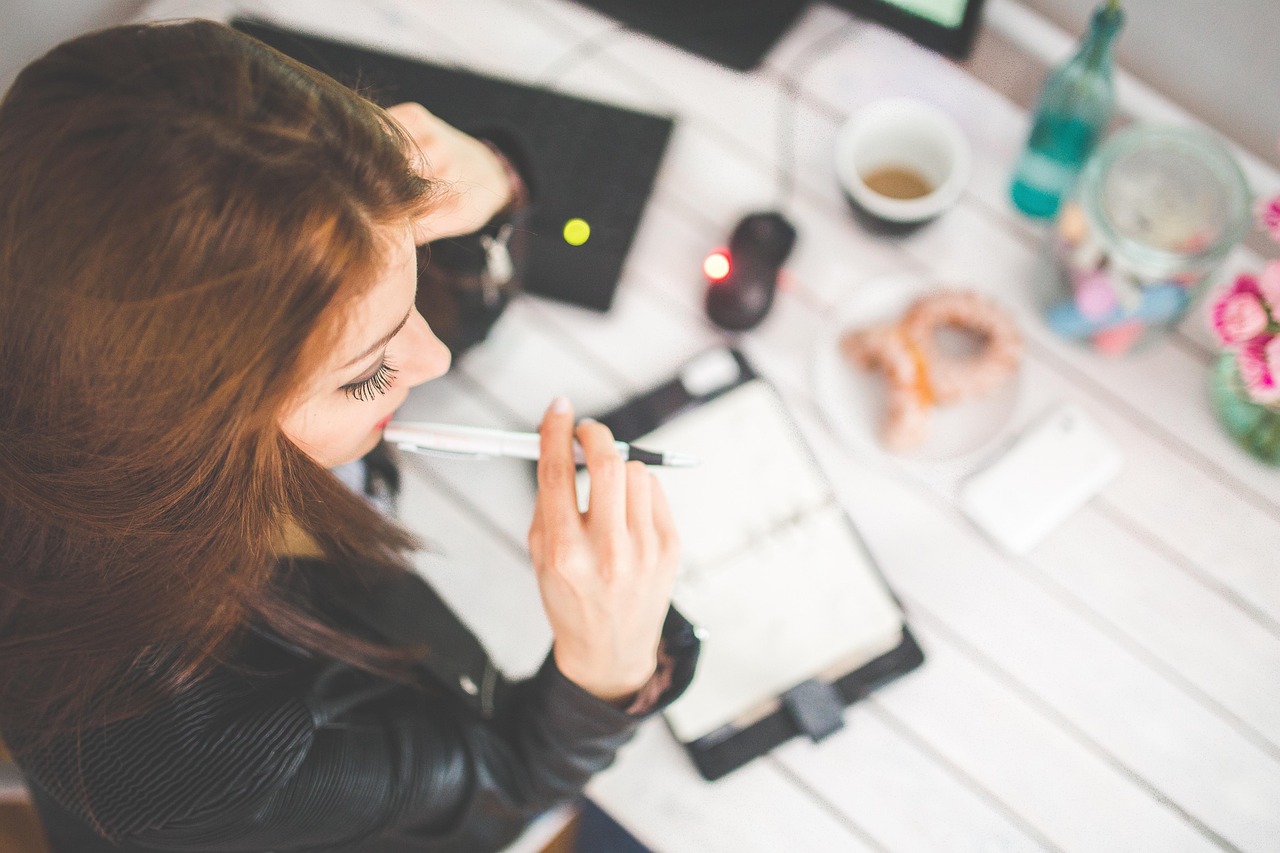vrouw achter haar bureau met een kop koffie werkend aan haar laptop